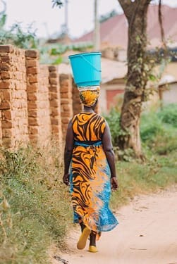 Konzept der Faszientherapie Rolfing - Schwerkraft verdeutlicht durch den geschmeidigen Gang einer afrikanischen Frau mit einer Last auf dem Kopf