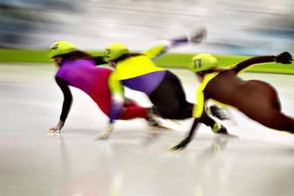 Eisschnellläufer im Rennen in einer Kurve. Sie zeigen wie Kufen auf Eis gleiten, sowie auch Faszien gleiten sollen.