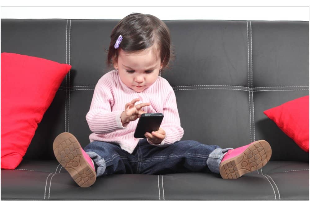 Little girl focusing on her mobile. Body awareness is lost through focusing and too little movement.